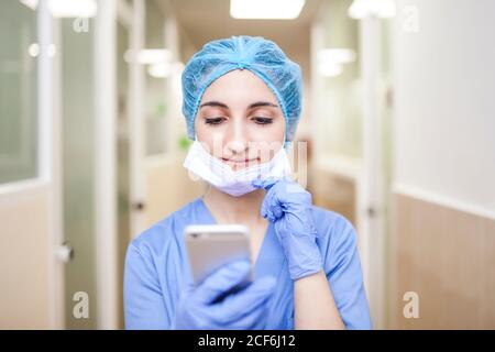femme chirurgien debout dans le couloir lors de la vérification des messages son smartphone Banque D'Images