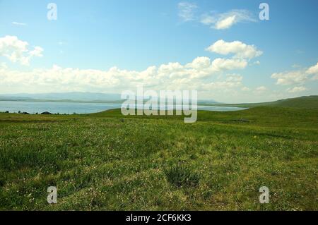 Longue steppe et plusieurs petites maisons sur le flanc d'une colline sur le rivage d'un grand lac pittoresque. Lac de Fyrkal, Khakassia, Sibérie du Sud, Russie. Banque D'Images