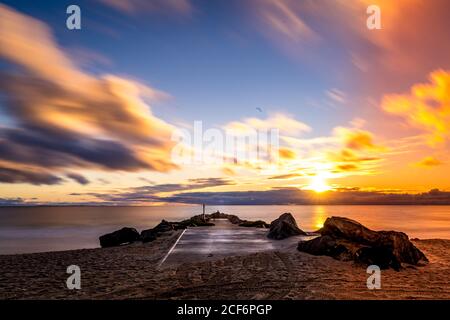 Magnifique coucher de soleil et nuages au bord de la mer avec bateau de pierre de jetée rampe Banque D'Images