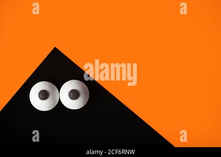 Arrière-plan Halloween, fantôme noir avec yeux renflés sur orange, espace de copie. Banque D'Images