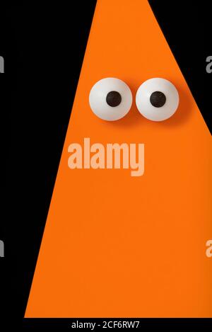 Arrière-plan Halloween, fantôme orange avec yeux renflés sur noir, espace de copie. Banque D'Images
