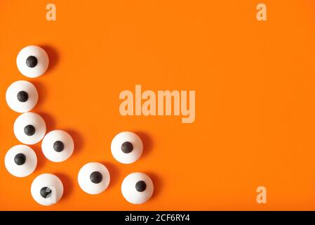 Arrière-plan Halloween, beaucoup d'yeux bulgés blancs sur fond orange, espace de copie. Banque D'Images