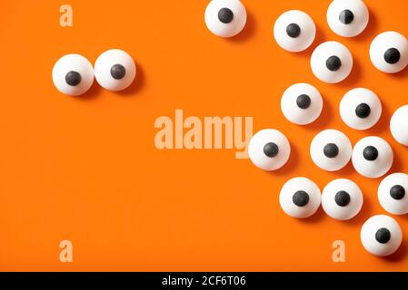 Arrière-plan Halloween, beaucoup d'yeux bulgés blancs sur fond orange, espace de copie. Banque D'Images