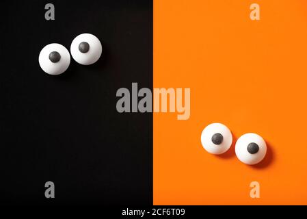 Drôle halloween design, deux paires d'yeux pendu dehors, orange et noir fond, espace de copie. Banque D'Images