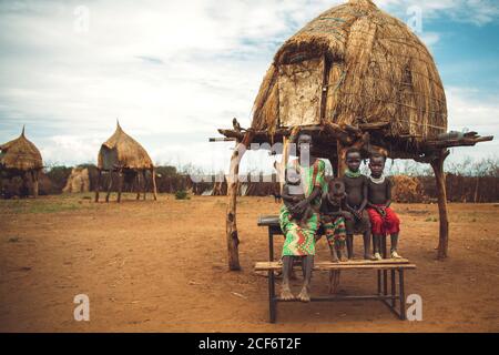 Omo Valley, Ethiopie - 08 novembre 2018: Femme et enfants de la tribu Nyangatom assis près de la cabane à paille dans le village. Omo Valley, Éthiopie Banque D'Images
