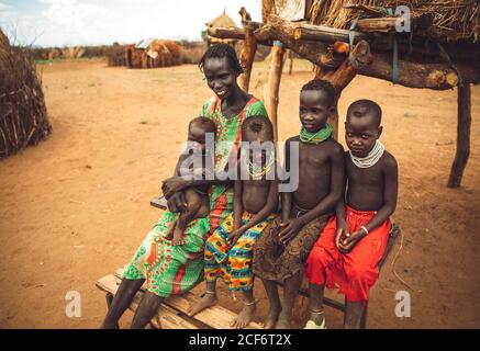 Omo Valley, Ethiopie - 08 novembre 2018: Femme et enfants de la tribu Nyangatom assis près de la cabane à paille dans le village. Omo Valley, Éthiopie Banque D'Images