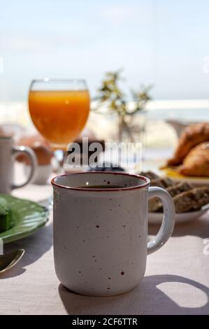 Petit-déjeuner complet maison servi au soleil avec thé ou café tasse et jus d'orange Banque D'Images