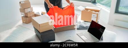 Boutique en ligne vendant des vêtements sur le site Web travaillant sur ordinateur portable ecommerce affaires de la maison. Femme emballage de nouveaux vêtements mode achat dans l'expédition Banque D'Images