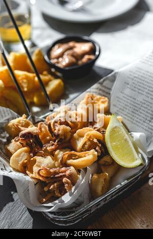 Par-dessus les petits pieuvres frits servis dans le panier de la friteuse avec une tranche de citron sur une table festive au restaurant Banque D'Images