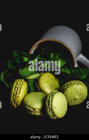 Macarons verts faits maison, vert avec menthe sur fond sombre. Nourriture sombre. Banque D'Images