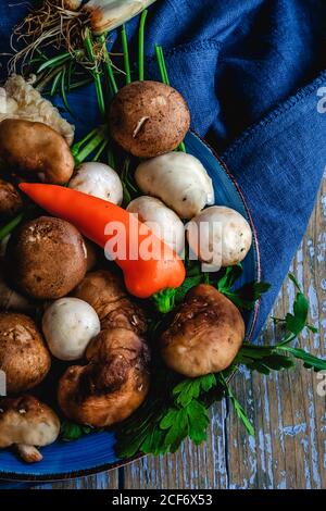 Assortiment de champignons sauvages avec oignons, piments, thym, romarin et basilic sur fond gris. Concept alimentaire végétalien. Macro Banque D'Images