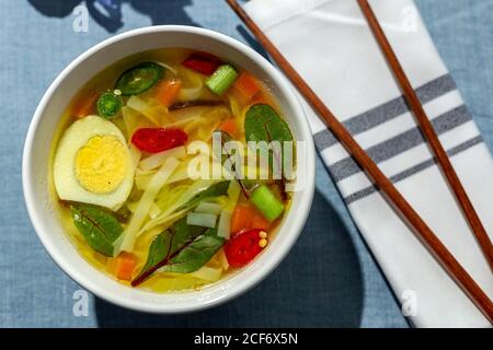 De dessus vue de dessus soupe orientale de nouilles ramen saines avec shiitake, épinards, carottes, oeufs et piments sur la table du restaurant Banque D'Images