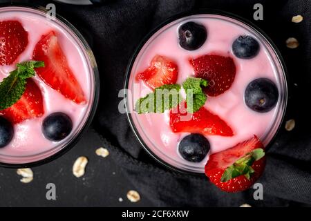 Yaourt maison avec fraises, bleuets et céréales avec fond sombre et lumière du soleil.concept alimentaire sain.nourriture végétarienne Banque D'Images