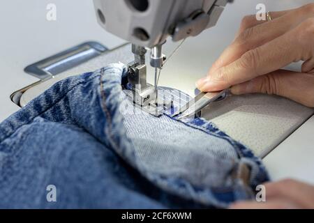 Femme travaillant mains dans une usine de textile couture sur une machine à coudre industrielle. Production industrielle Banque D'Images