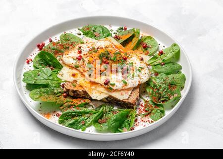 Pain grillé maison avec œuf frit, épinards et herbes aromatiques sur fond blanc.nourriture végétarienne.concept alimentaire sain. Banque D'Images
