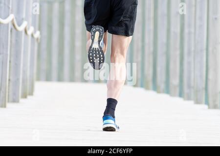 Court sportif masculin non reconnaissable en t-shirt et short bleus courir à l'extérieur sous couvert Banque D'Images