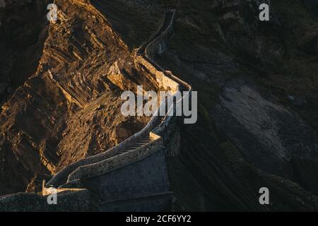 D'en haut merveilleux paysage avec chemin menant le long du pont en pierre avec des escaliers au sommet de la montagne le long de la crête rocheuse dedans soirée ensoleillée Banque D'Images