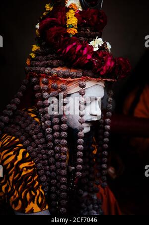 Allahabad City, Inde - FÉVRIER, 2018: Hindou sadhu Saint homme avec visage peint portant un costume traditionnel coloré assis sur le tapis pendant le festival Prayag Kumgh Mela Banque D'Images