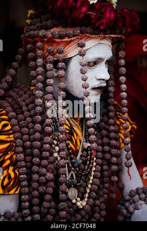 Allahabad City, Inde - FÉVRIER, 2018: Hindou sadhu Saint homme avec visage peint portant un costume traditionnel coloré assis sur le tapis pendant le festival Prayag Kumgh Mela Banque D'Images