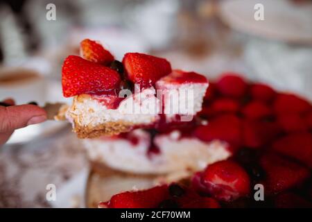 Femme coupant à la main gâteau de fraise avec couteau Banque D'Images