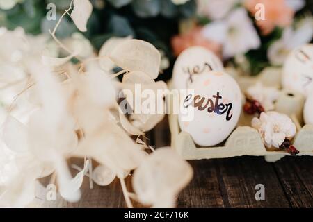 Oeufs de Pâques peints à la main par des enfants avec des messages dans un coquetier sur une table en bois Banque D'Images