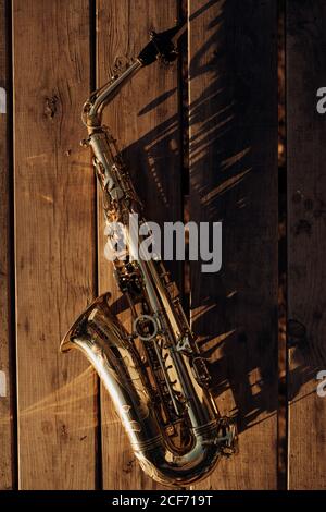 saxophone doré couché sur un vieux bois brillant dans le lumière du soleil Banque D'Images