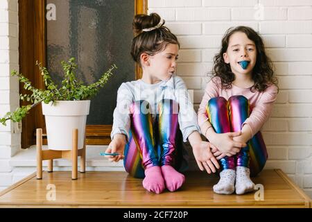 Deux sœurs souriantes qui sortent une langue bleue après avoir mangé une gomme à bulles bleue Banque D'Images