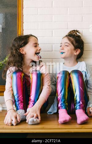 Deux sœurs souriantes qui sortent une langue bleue après avoir mangé une gomme à bulles bleue Banque D'Images