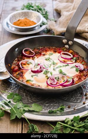 Shakshuka parfumé avec rondelles d'oignon dans une casserole Banque D'Images