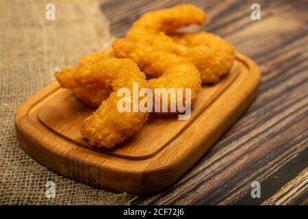 Crevettes de l'Atlantique frites dans de la pâte sur un plateau de service en bois. Gros plan Banque D'Images