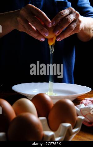 une femelle méconnaissable cassant un œuf de poulet frais dans un bol pendant la cuisson pâtisserie dans la cuisine Banque D'Images
