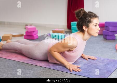 Vue latérale d'une brunette sportive flexible concentrée dans les vêtements de sport pose de yoga couché sur un tapis Banque D'Images