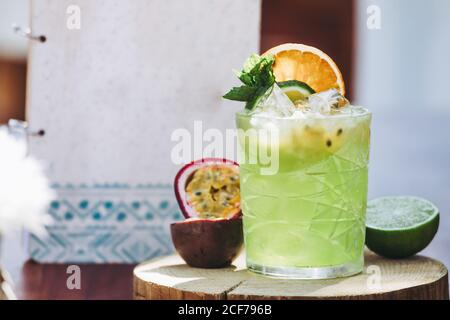 Verre d'alcool vert froid Mojito cocktail avec passion fraîche fruits et citron vert garni de feuilles de menthe et de tranches de fruits Banque D'Images