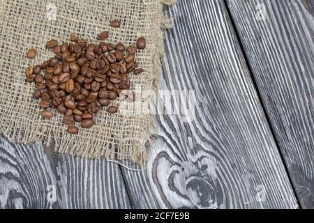 Grains de café sur linge grossier. Sur une surface de planches de pin brossé peintes en noir et blanc. Banque D'Images