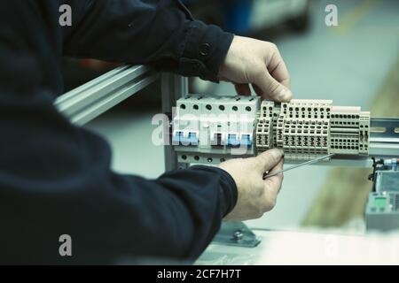 électricien sans visage en chemise noire avec sonde de multimètre appareillage électrique à réparation manuelle Banque D'Images