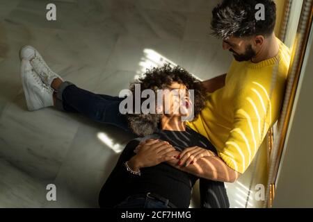 Jolie femme afro-américaine aux yeux fermés, paisiblement allongée genoux d'un homme barbu dans une pièce élégante Banque D'Images