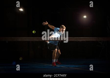 homme jouant padel dans l'obscurité Banque D'Images