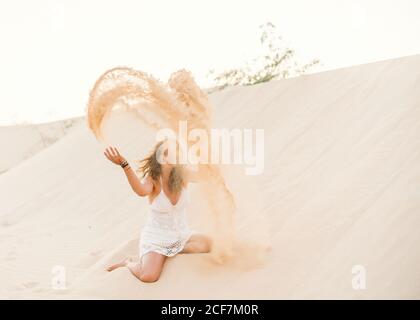 Femme ayant plaisir à jeter du sable dans le désert Banque D'Images