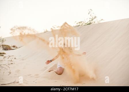 Femme ayant plaisir à jeter du sable dans le désert Banque D'Images