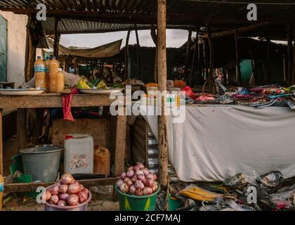Gambie, Afrique - 3 août 2019: Stand avec différents plats traditionnels naturels et boissons aussi avec des vêtements et des choses sous le toit dans le bazar de rue Banque D'Images