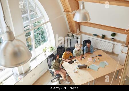 Groupe de programmeurs assis à la table et regardant pc portable ils développent de nouveaux logiciels en équipe dans la salle de conseil Banque D'Images