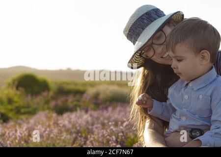 Grande famille, paternité, enfance, maternité, concept de style provençal - Happy Young MOM s'assoit sur une chaise en osier avec un petit enfant garçon fils sur la lavande Banque D'Images