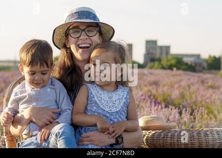 Grande famille, paternité, enfance, maternité, concept de style provençal - jeune maman est assise sur une chaise en osier avec un petit garçon fils et fille sur Banque D'Images