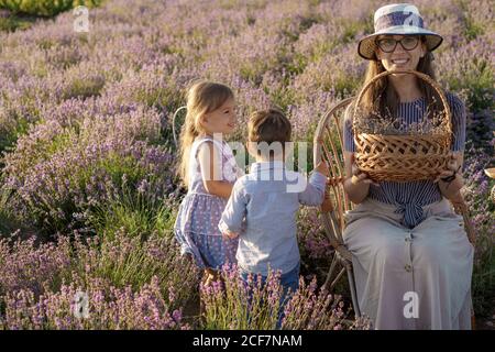 Grande famille, paternité, enfance, maternité, concept de style provençal - jeune maman est assise sur une chaise en osier avec un petit garçon fils et fille sur Banque D'Images