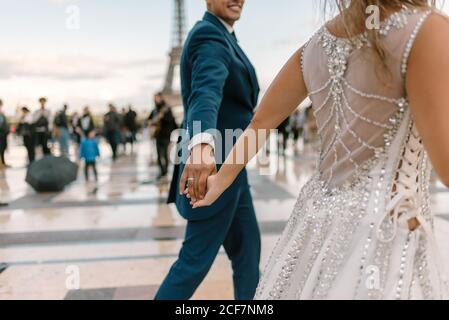 Marié en costume bleu et mariée en robe de mariée blanche danser lentement en souriant et en regardant les uns les autres avec La Tour Eiffel en arrière-plan à Paris Banque D'Images