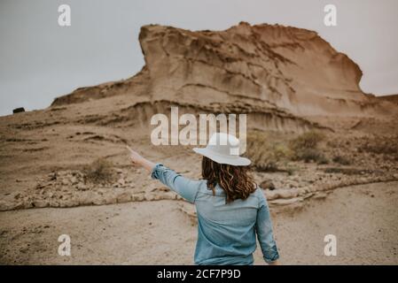 Vue arrière d'une femme méconnaissable vêtue de vêtements décontractés sur les dunes de sable du désert et montrant le jour sombre Banque D'Images