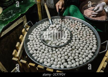 Du dessus de la récolte chef sans visage préparant des boules de viande dans grande casserole en métal avec pinces et louche Banque D'Images