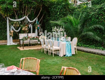 Décoration pour cérémonie de mariage en plein air avec table à dîner couleurs bleu et blanc et cadre de mariage sur le jardin avec plantes tropicales vertes Banque D'Images