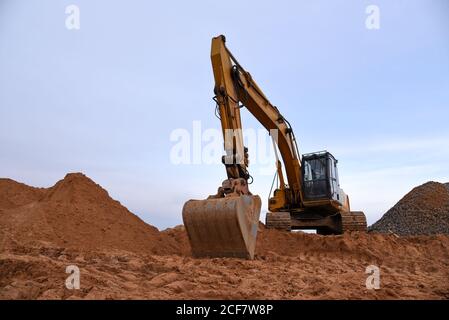 Pelle hydraulique à chaînes pendant les travaux de terrassement dans les exploitations minières à ciel ouvert. Chargeuse avec godet dans une carrière de sable. Pelle rétro creusant le sol pour la fondatrice Banque D'Images