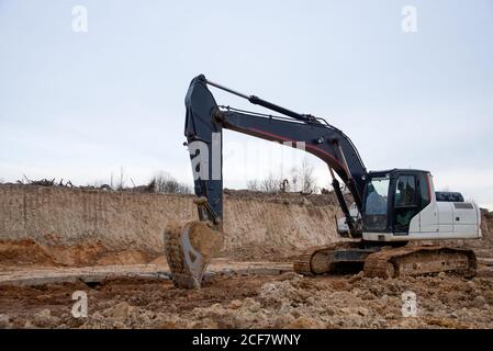 Pelle hydraulique à chaînes pendant les travaux de terrassement dans les exploitations minières à ciel ouvert. Chargeuse avec godet dans une carrière de sable. Pelle rétro creusant le sol pour la fondatrice Banque D'Images